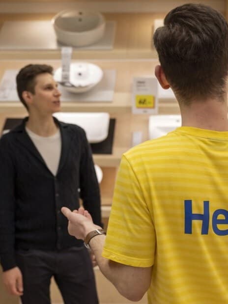 Ein Mann lässt sich in der Badezimmerabteilung von einem IKEA Mitarbeiter beraten.