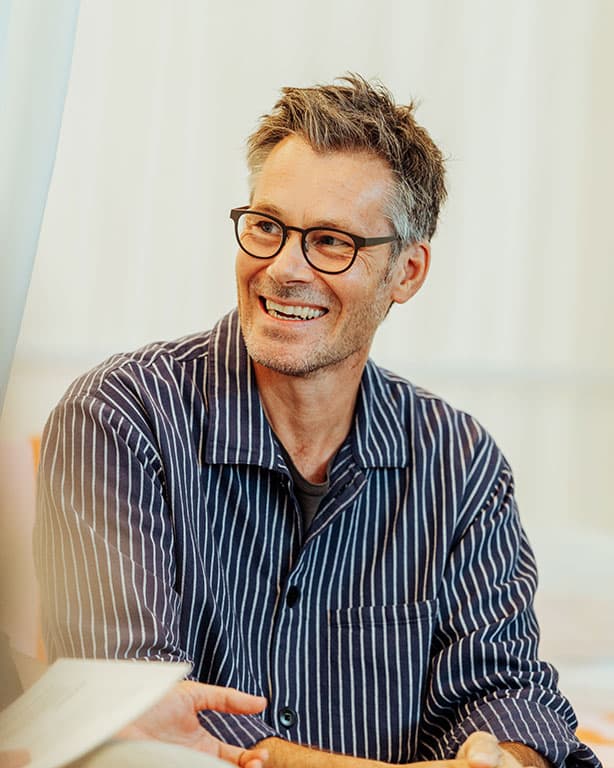 Ein Mann mit einem dunkelblauem Karriertem Hemd und einer schwarzen Brille