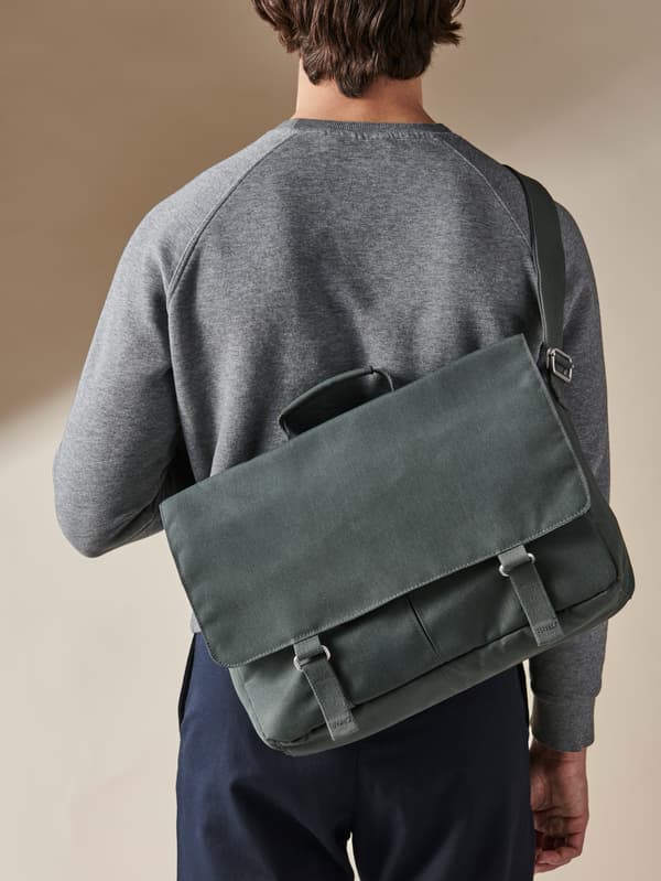 Ein Mann mit Grauem Pullover trägt eine DRÖMSÄCK Schultertasche auf dem Rücken