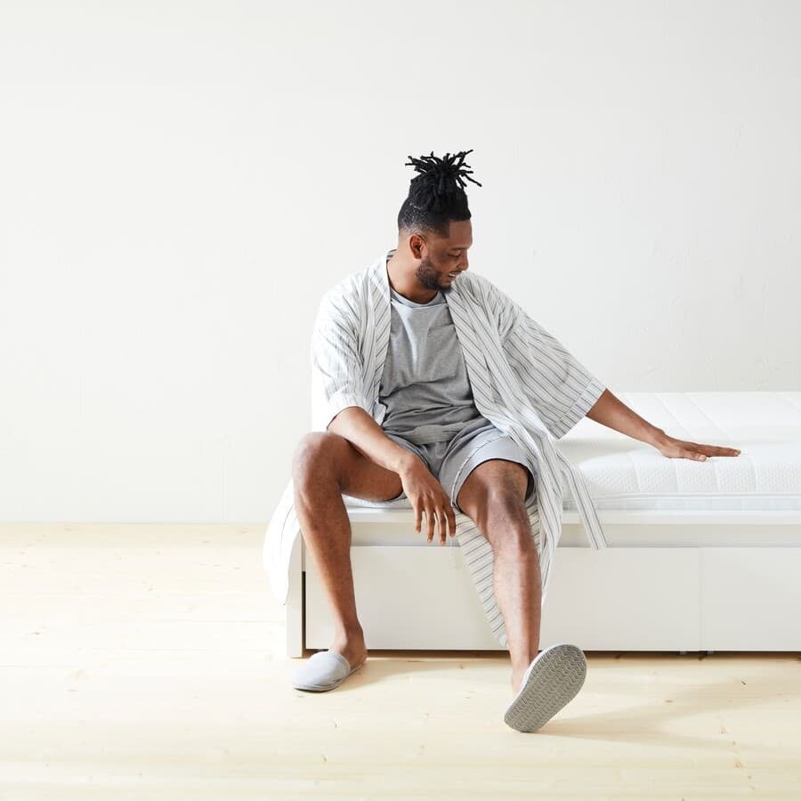 Ein Mann sitzt auf einer Matratze.