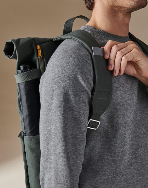 Ein Mann trägt einen olivgrünen DRÖMSÄCK Rucksack und zieht eine Karte aus dem Kartenfach an einem der Schultergurte.