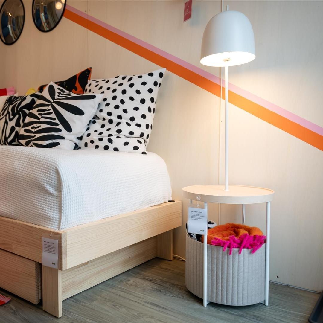 Ein Nachtkästchen in Kombination mit einer Leuchte neben einem Bett.