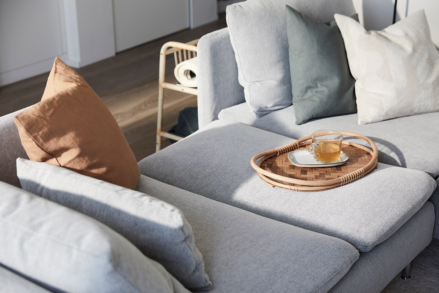 Ein Rattantablett auf einem hellgrauen Sofa 