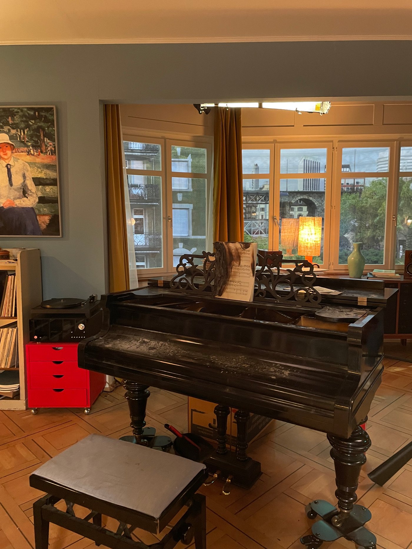 Ein schwarzer Flügel mit Hocker davor steht in einem Wohnzimmer.