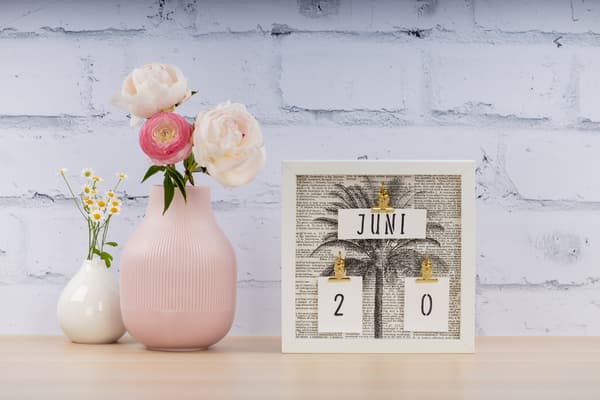 Ein selbstgebastelter Kalender steht neben einer Vase.