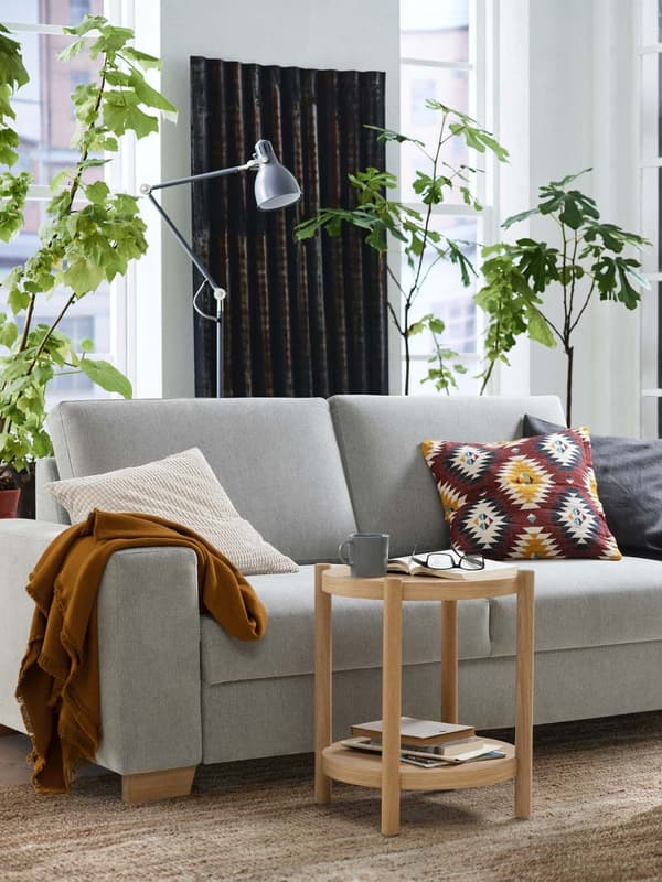 Ein SÖRVALLEN 2er Sofa steht vor einer hellen Wohnzimmerwand. Davor steht ein kleiner runder Beistelltisch. 