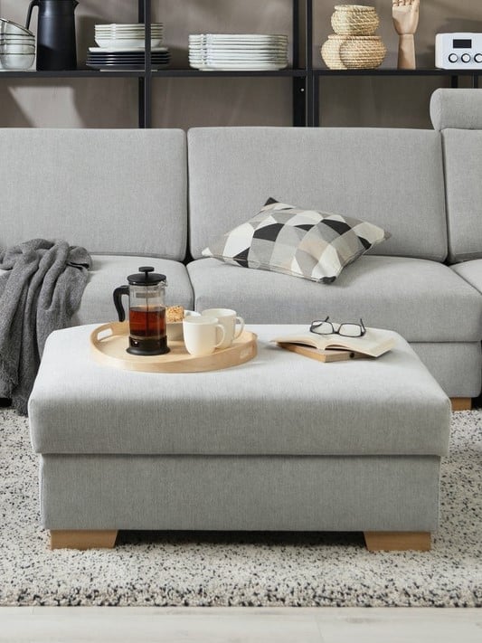 Ein SÖRVALLEN Hocker steht vor einem Sofa. Er dient gleichzeitig als Couchtisch.