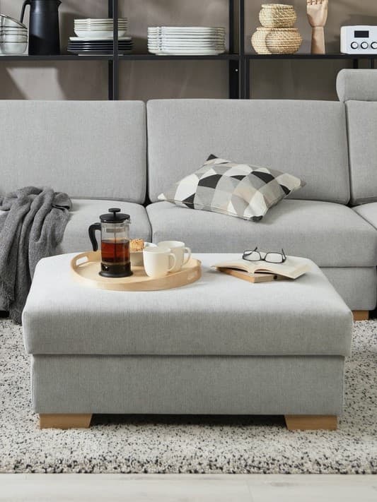 Ein SÖRVALLEN Hocker steht vor einem Sofa. Er dient gleichzeitig als Couchtisch. 