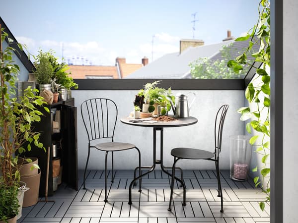 Ein sonniger Balkon mit schwarzem Bistro Tisch und Stühlen