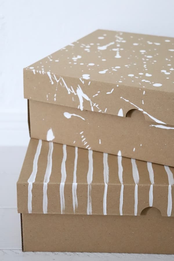 Ein Stapel von zwei VATTENTRÅG Kästen aus braunem Kraftpapier. DIe Kästen wurden dekorativ mit weißer Farbe bemalt.