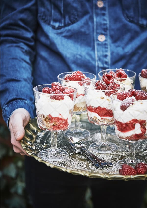 Ein Tablet mit Käsekuchen im Glas mit Himbeeren.