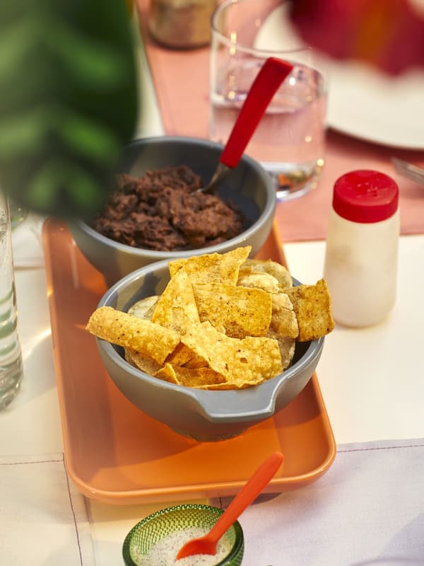 Ein Tablett mit 2 Schälchen. Gefüllt mit Dip und Nachos. 