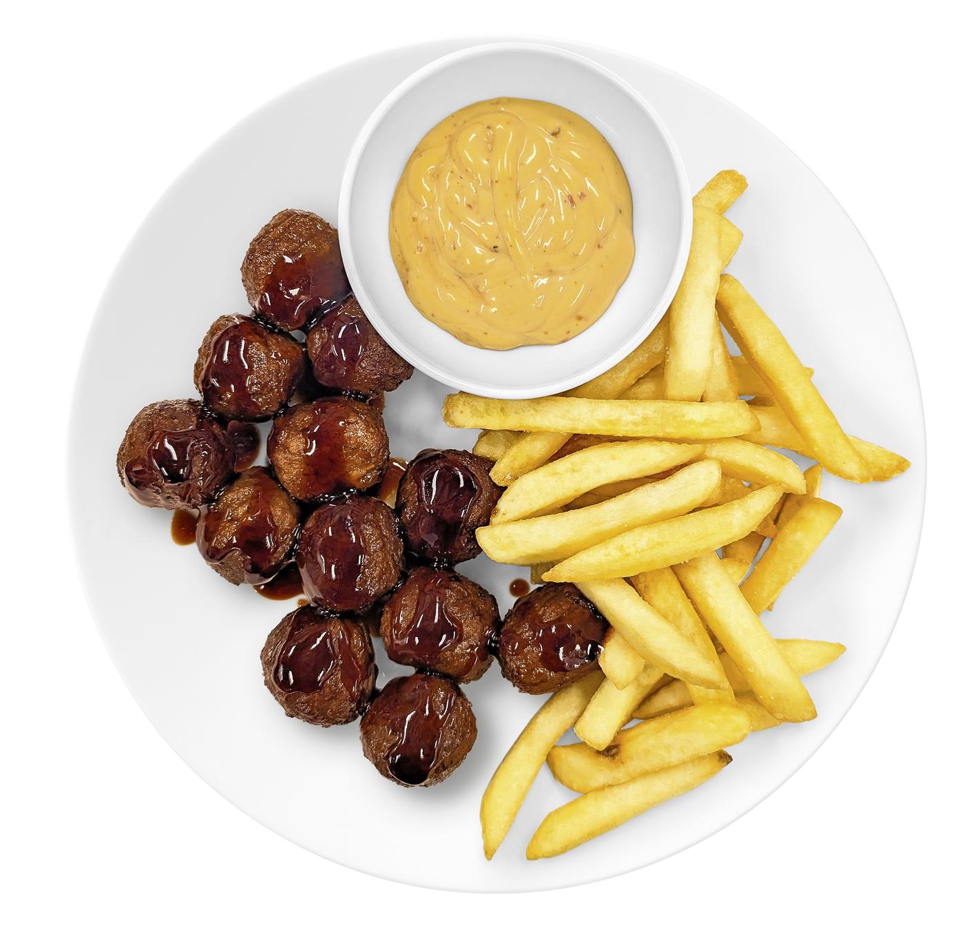 Ein Teller mit FLeischbällchen, Pommes Frites und einer gelben Soße.