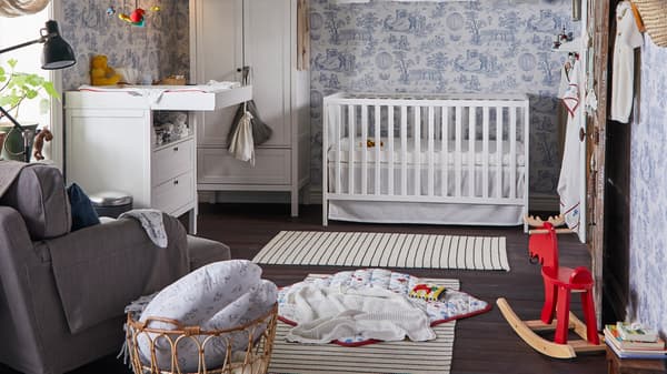 Ein traditionelles Babyzimmer mit weißem Kleiderschrank, Babydecke, Spielbereich, Leseleuchte und Wickeltisch.