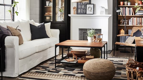 Ein traditionelles Wohnzimmer mit einem Bücherschrank und einer TV-Bank aus schwarzbrauner/massiver Kiefer, einem weißen Sofa und einem Glastürenschrank.