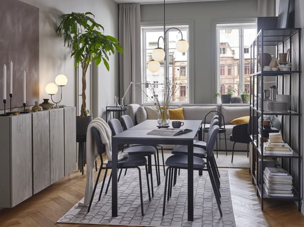 Ein VANGSTA Ausziehtisch in einem Esszimmer auf einem geometrisch gemusterten Teppich. Über dem Tisch ist eine dreiarmige Hängeleuchte zu sehen.