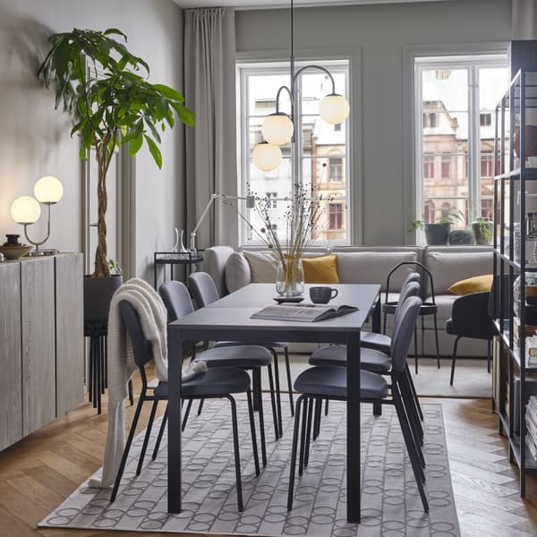 Ein VANGSTA Ausziehtisch in einem Esszimmer auf einem geometrisch gemusterten Teppich. Über dem Tisch ist eine dreiarmige Hängeleuchte zu sehen.