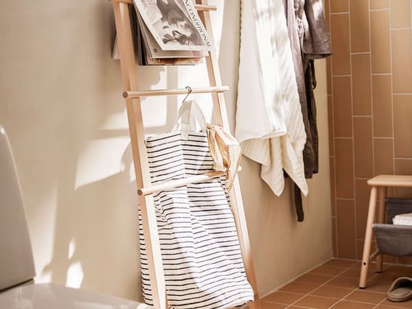 Ein VILTO Leiterregal und ein VILTO Hocker in einem beigebraun gefliesten Bad mit Handtüchern an der Wand.