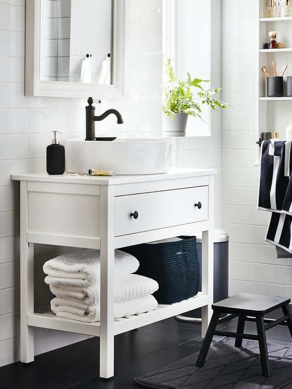 Ein weißer HEMNES Waschtisch im Landhausstil steht vor einer weißen Badezimmerwand. Darüber hängt der passende Spiegel.