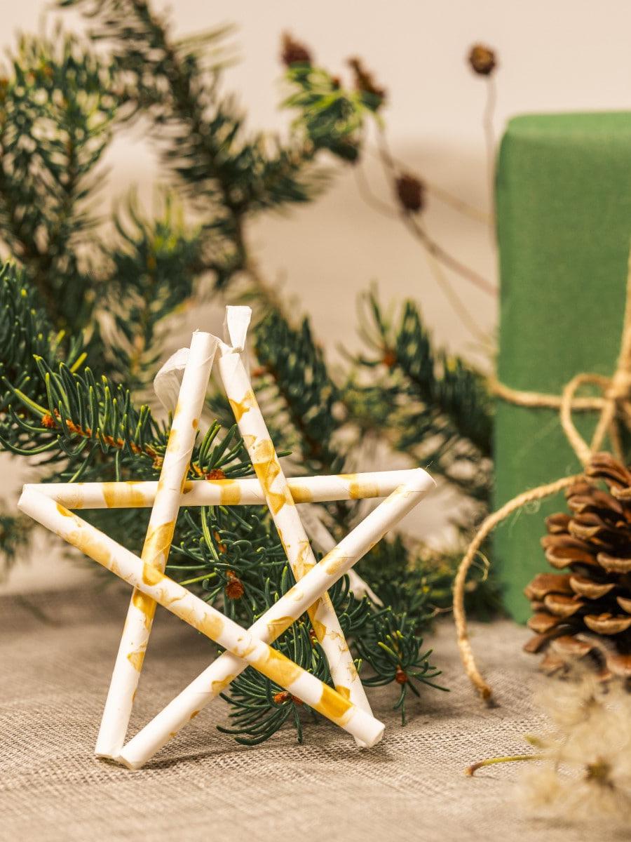Ein weißer Holz Stern liegt an einer Wand.