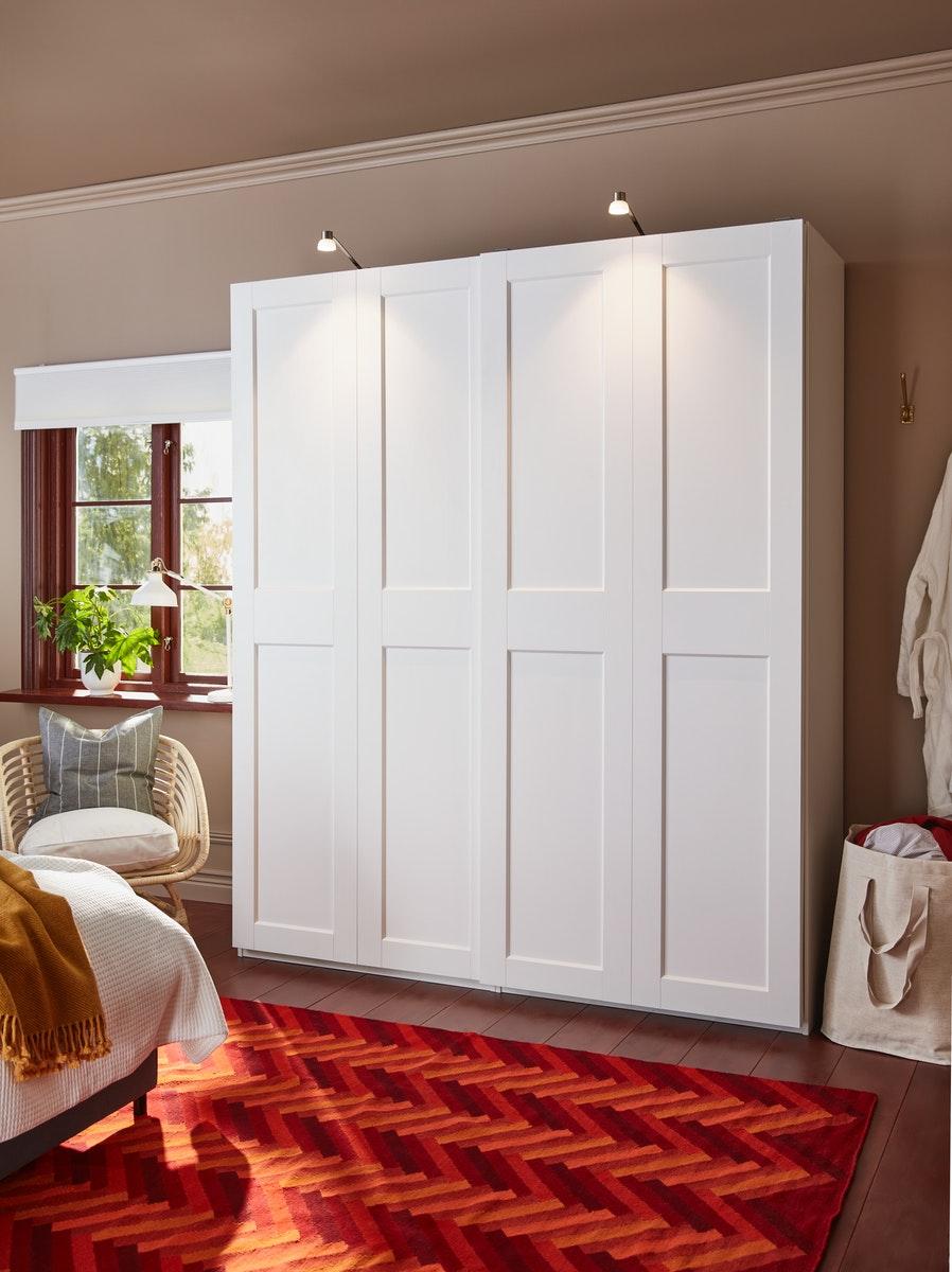 Ein weißer PAX Schrank in einem Schlafzimmer. Ein roter Teppich zwischen Bett und Schrank.