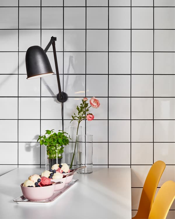 Ein weißer Tisch mit einer SKURUP Arbeits-/Wandleuchte in Schwarz