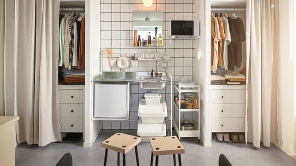 Ein Wohnheimdoppelzimmer mit einer SUNNERSTA Miniküche zwischen zwei Schränken. Die Schränke werden mit Gardinen geschlossen.