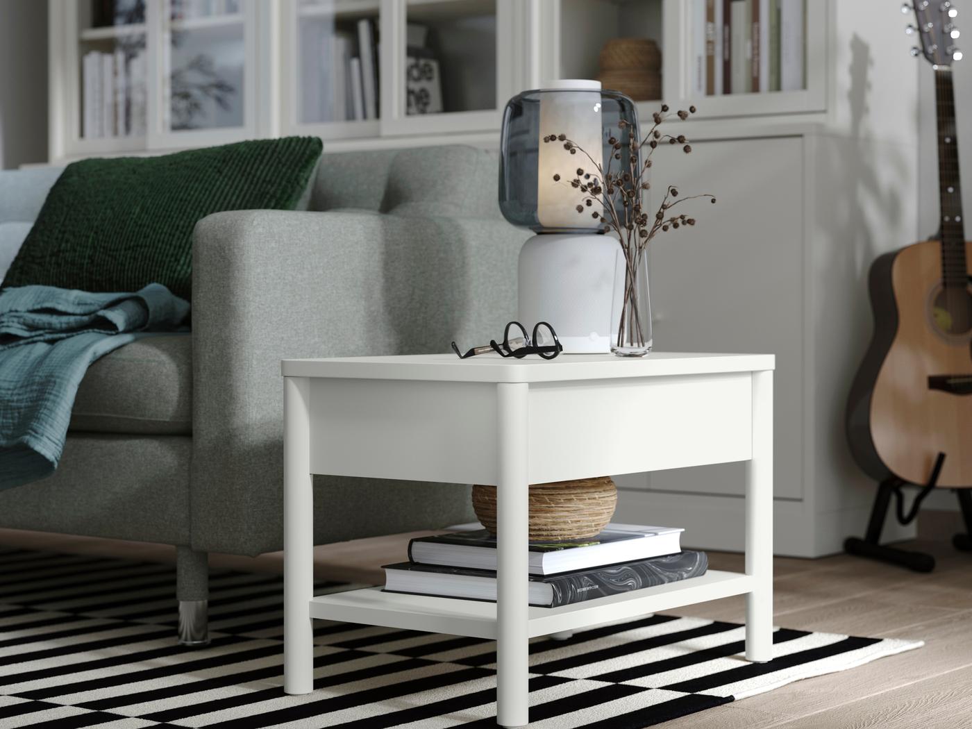 Ein Wohnzimmer Ausschnitt, zu sehen ein schwarz-weißer Teppich, dahinter ein Sofa. Zentral ein weißer Sofa Beistelltisch von IKEA