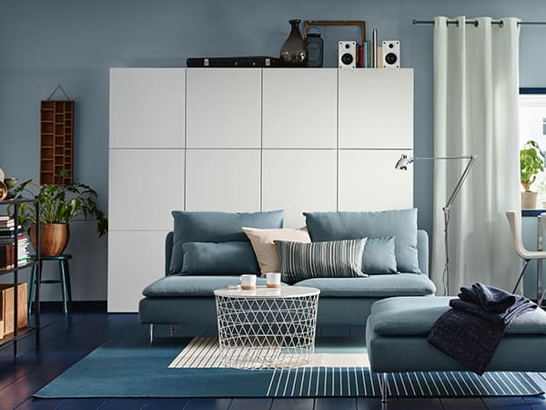 Ein Wohnzimmer in Blautönen mit einer weißen Schrankwand im Hintergrund.