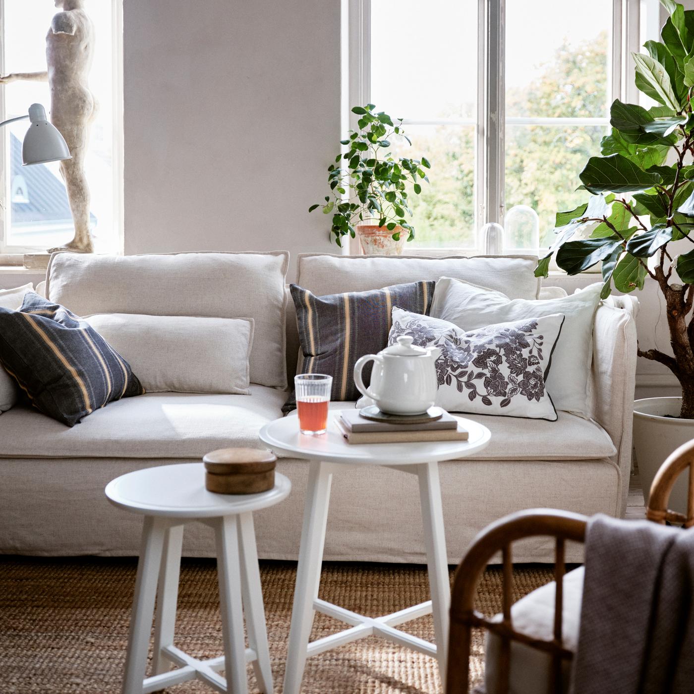 Ein Wohnzimmer mit einem SÖDERHAMN Sofa, auf dem verschiedene Kissen liegen – eines davon ein SKUGGNÄVA Kissen mit Blumenmuster.