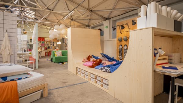 Einblick in den Ausstellungsraum von IKEA auf den Köln Passagen. Rechts im Bild eine Halfpipe aus Holz, links im Bild ein Bett mit Matratze und Kissen.
