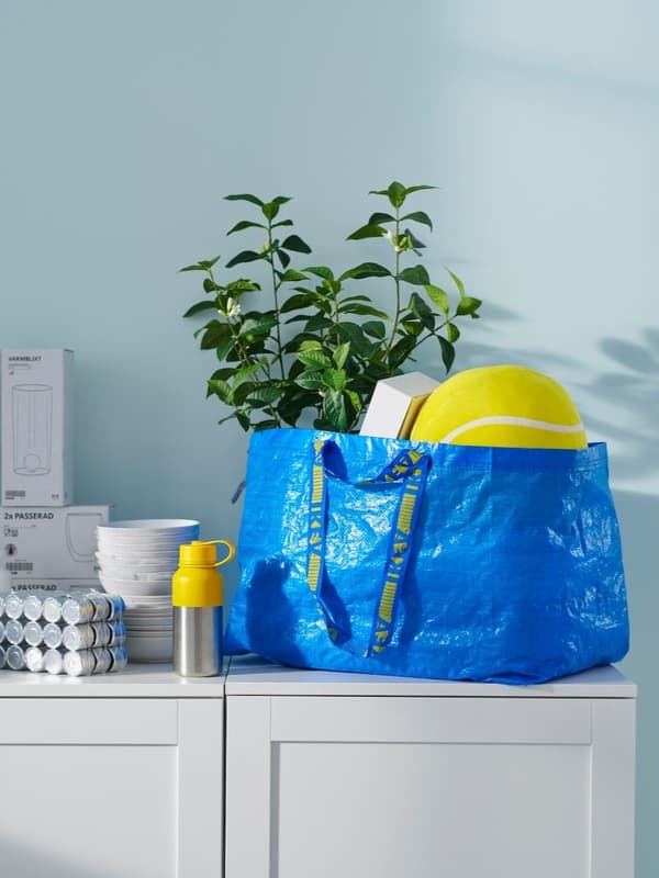 Eine blaue FRAKTA Tüte steht auf einem Sideboard.