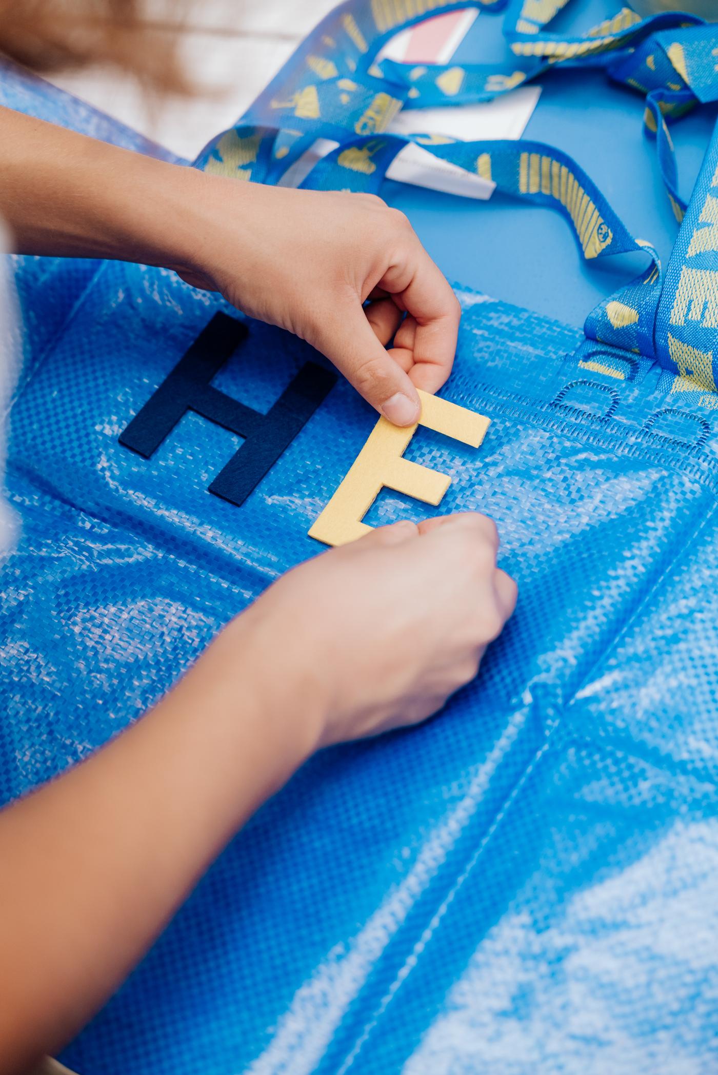 Eine blaue IKEA FRAKTA Tasche wird mit Buchstaben personalisiert.