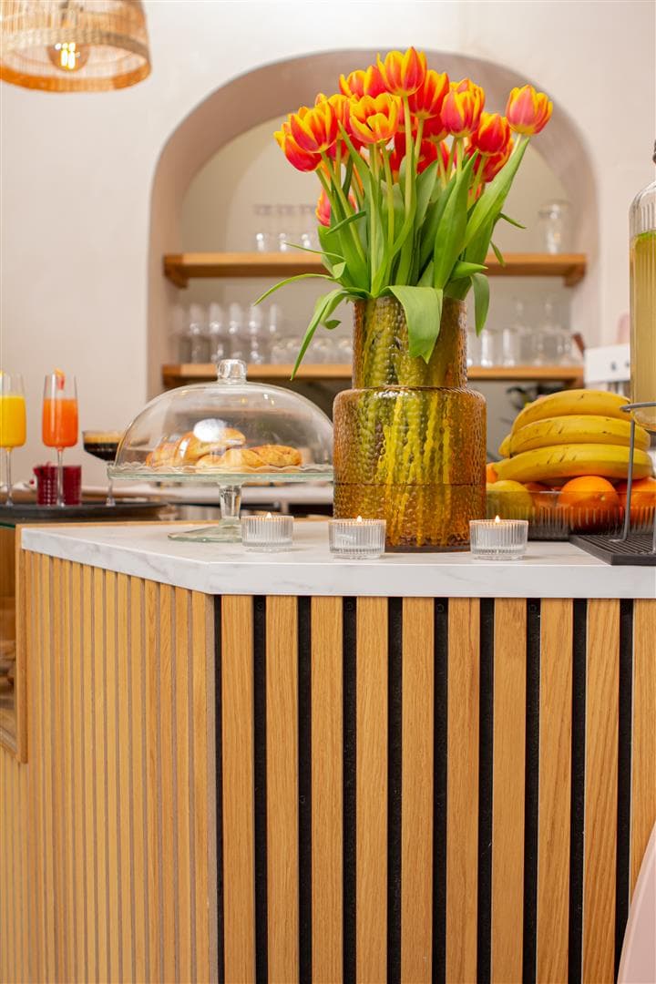 Eine Blumenvase mit frischen Tuplen und ein Kuchenteller mit Glasabdeckung stehen auf einer Café-Theke mit weißer Maßarbeitsplatte von IKEA.