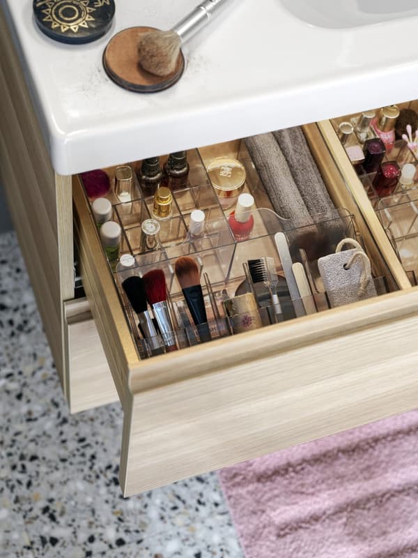 Eine Box gefüllt mit Make Up und Kosmetikartikeln in einem Badezimmerunterschrank. 