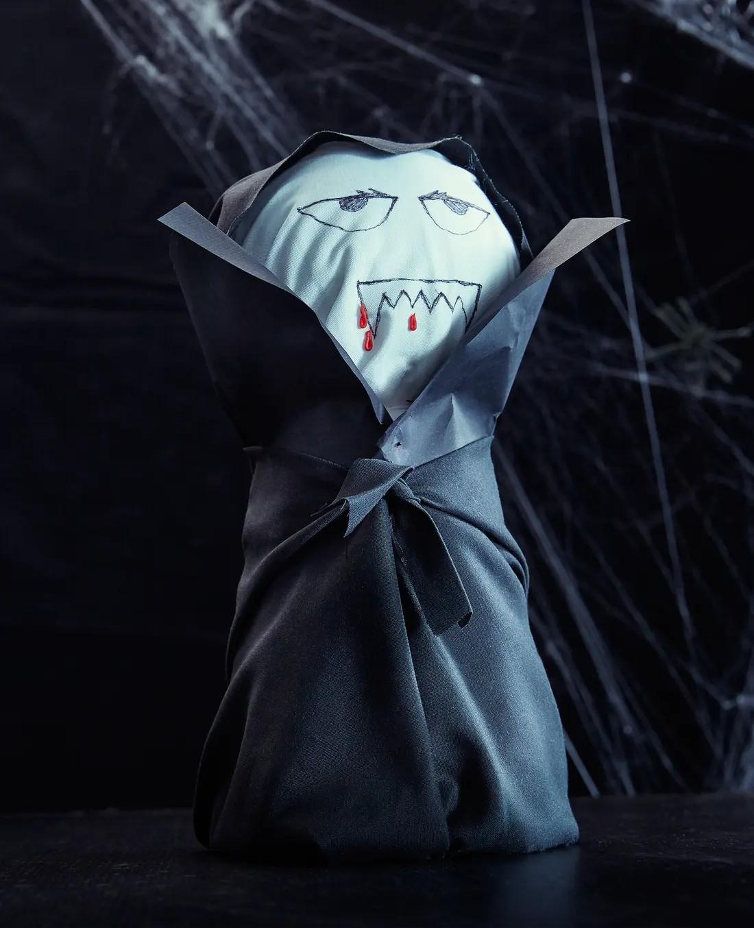 Eine DIY Dracula Puppe steht vor einem schwarzen Hintergrund.