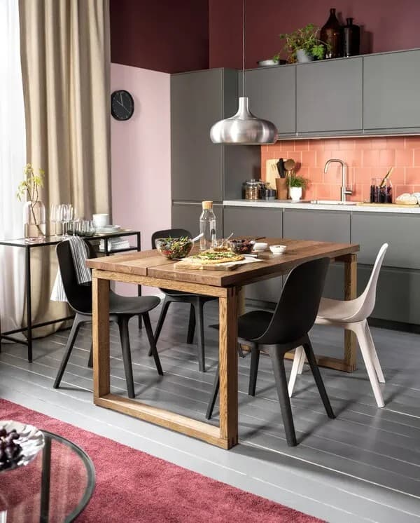 Eine dunkelgraue Küche, davor ein MÖRBYLÅNGA Esstisch, unterschiedliche Stühle und eine Hängeleuchte.