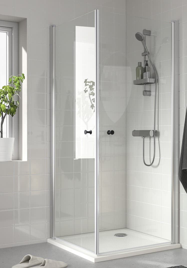 Eine Duschkabine mit Glaswänden in einem weißen Bad