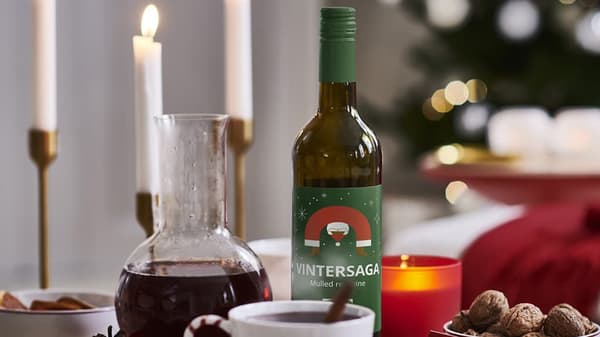 Eine Flasche GLÖGG mit Häferl und Kerzen auf weihnachtlich gedeckten Tisch