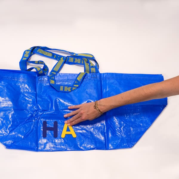 Eine FRAKTA Tasche auf die eine Person gerade Buchstaben aufklebt.
