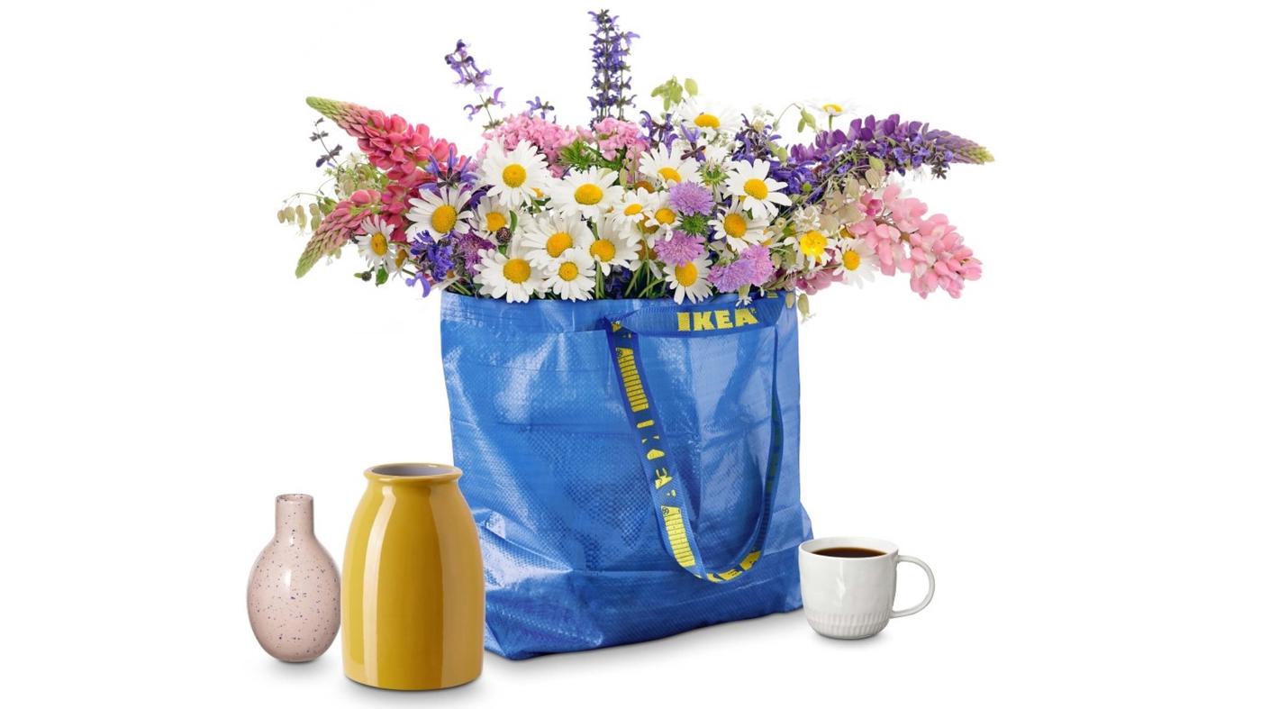 Eine FRAKTA Tasche gefüllt mit Blumen, zwei Vasen und einer Tasse gefüllt mit Kaffee.