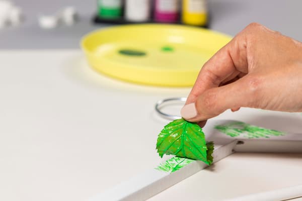 Eine Frau drückt das Blatt mit der Farbe auf einen weißen Kleiderbügel