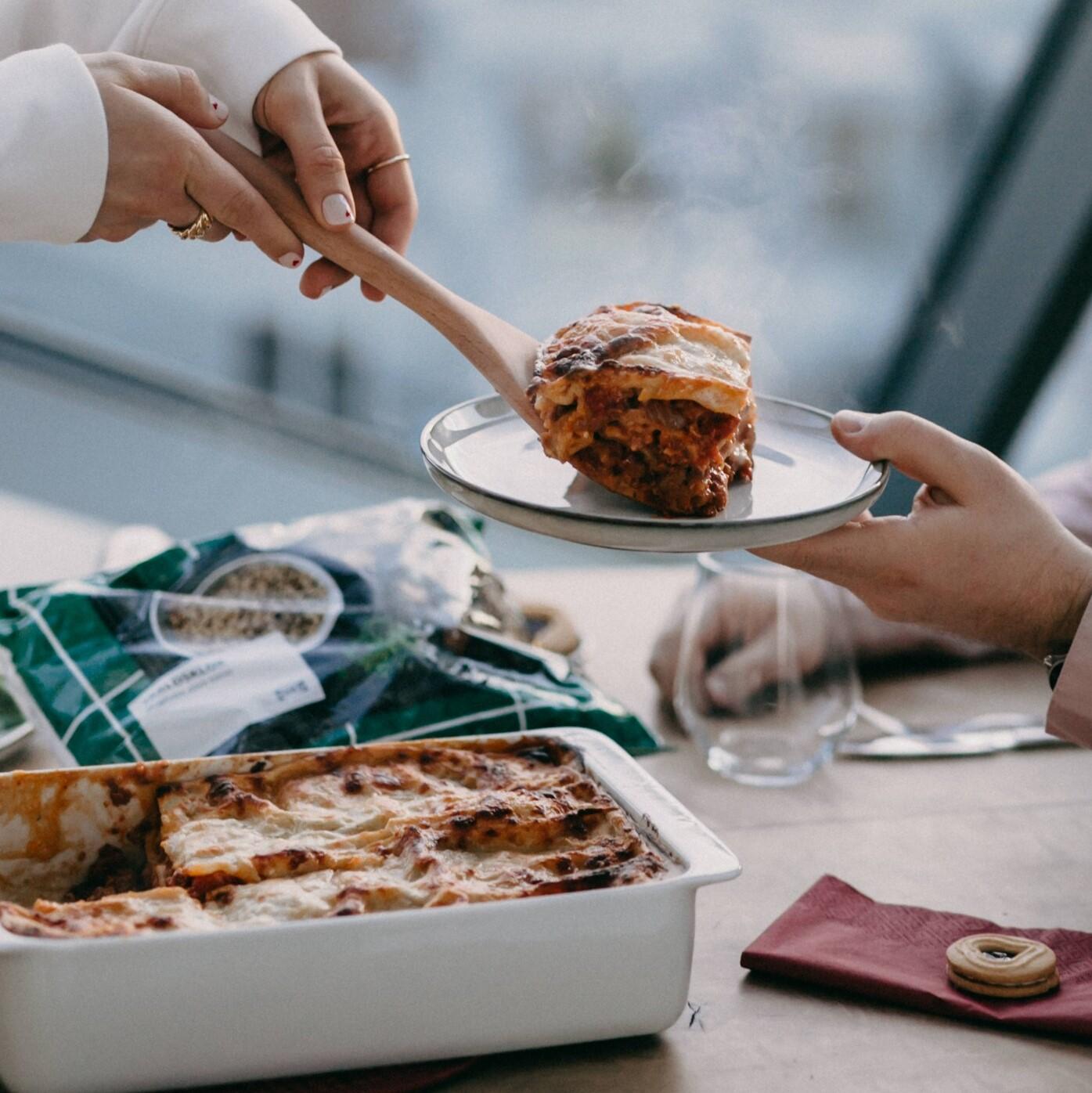 Eine Frau gibt aus einer Form etwas mit einem Kochlöffel auf einen anderen Teller.