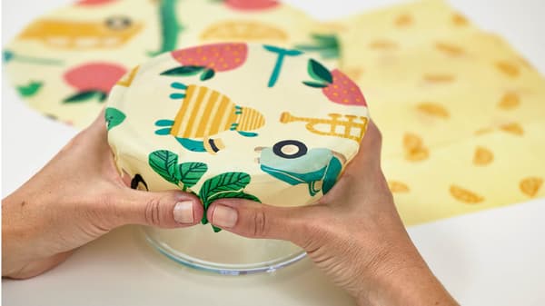 Eine Frau hält das Bienenwachspapier auf ein Glas damit es diese Form annimt.