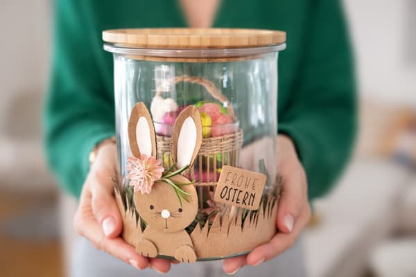 EIne Frau hält ein DIY Osterglas als Geschenk für das Osterfest in den Händen. 