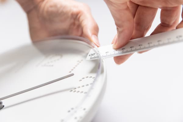 Eine Frau hält ein Lineal an die Uhr auf der Seite.