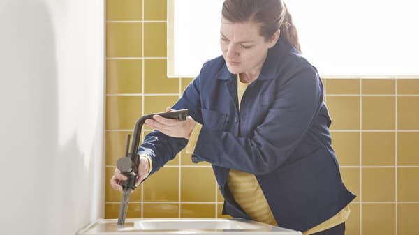Eine Frau installiert eine Mischbatterie an einem Waschbecken.