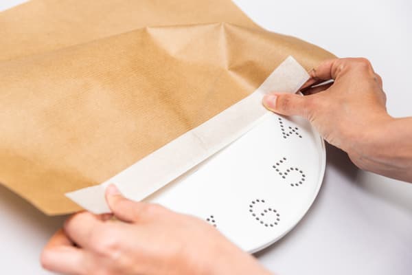Eine Frau klebt ein Papier auf die obere Hälfte der Uhr,.