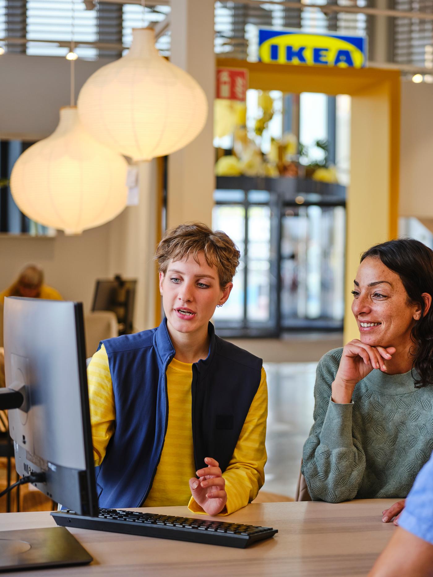 Eine Frau lässt sich von einem IKEA Mitarbeitenden zur Badplanung beraten.