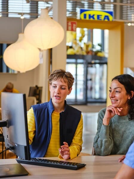 Eine Frau lässt sich von einem IKEA Mitarbeitenden zur Badplanung beraten.